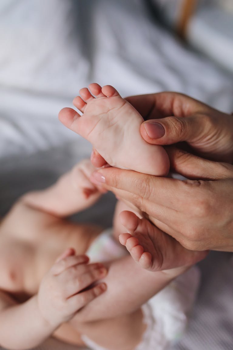 A close-up of a parent's hands gently massaging a baby's feet, showcasing tenderness and care.